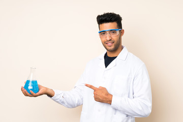 Young handsome man over isolated background with a scientific test tube and pointing it
