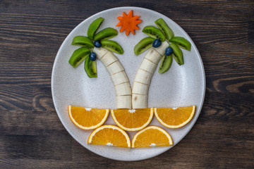 Creative fruit dessert with kiwi, banana, grape, carrot and orange. Concept children food. Fun...