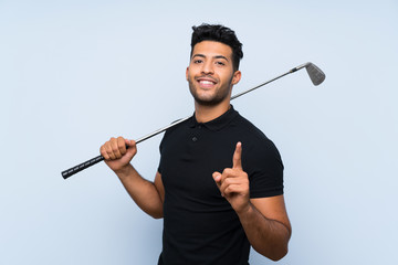 Handsome young man playing golf over isolated blue background pointing up a great idea