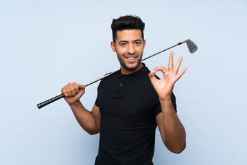 Handsome young man playing golf over isolated blue background showing ok sign with fingers