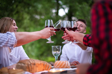 happy friends toasting red wine glass during french dinner party outdoor