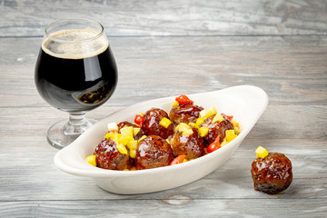Close up of glistening balls on an appetizer serving dish and a frosty glass of dark beer