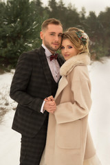 the couple is hugging and close to the kiss, holding hands, a bouquet in their hands. A suit with a butterfly and a coat with a dress. The bride and the groom