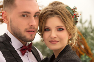 the couple is hugging and close to the kiss, holding hands, a bouquet in their hands. A suit with a butterfly and a coat with a dress. The bride and the groom
