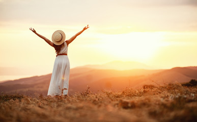 Happy woman standing with her back on sunset in nature  . - 295522408