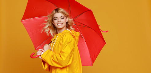 young happy emotional cheerful girl laughing  with red umbrella   on colored yellow background
