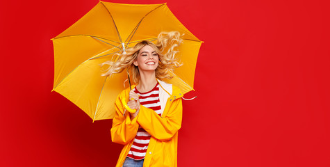 young happy emotional cheerful girl laughing and jumping with yellow umbrella   on colored red...