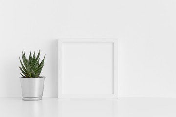 White square frame mockup with a cactus in a pot on a white table.