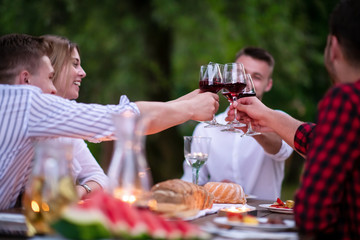 happy friends toasting red wine glass during french dinner party outdoor