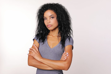 Reserved woman. Serious adult woman with tanned complexion and Afro hairstyle is looking to the camera with her arms folded.