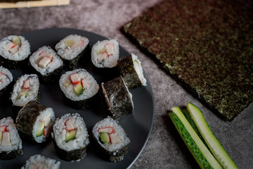 homemade sushi rolls with crab meat and cucumbers on dark background