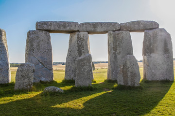 Standing stones of Stonehenge-the worlds most famous prehistoric monument - Closeup from inside the circle with dramatic shadows and Salisbury Plain in distance