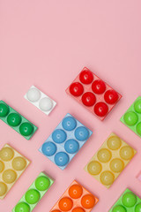 Plastic building blocks isolated on pink background. Top view with copy space for text. Flat lay