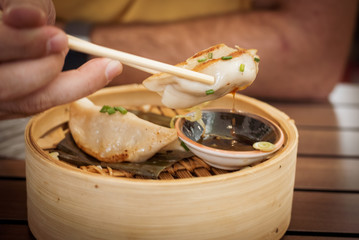 Thai food. mixed chicken, shrimp and vegetable gyozas in a Thai steamer with soy sauce in a black...