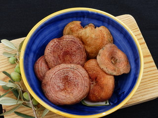 Mushrooms inside a blue ceramic bowl on a wooden table with a black background.