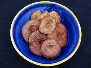Mushrooms inside a blue ceramic bowl with a black background.