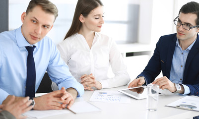 Group of business people discussing questions at meeting in modern office. Managers at negotiation or brainstorm. Teamwork, partnership and business concept