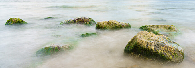 Meer überspült Steine mit Moos