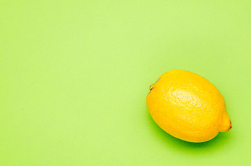 one yellow lemon on a green background