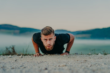 Fit man doing push ups exercise at outdoor gym. Core body workout athlete planking or doing pushup on grass.