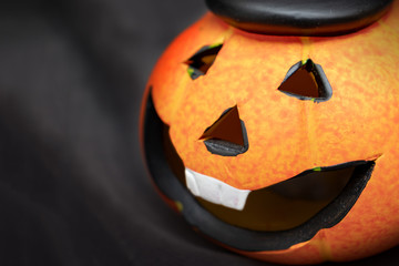 Halloween pumpkin with spooky smiling face on dark black background wiyh copy space