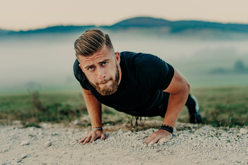 Fit man doing push ups exercise at outdoor gym. Core body workout athlete planking or doing pushup on grass.