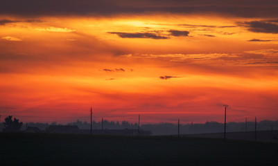 Fototapeta na wymiar Très beau ciel orange sur un champ en campagne.