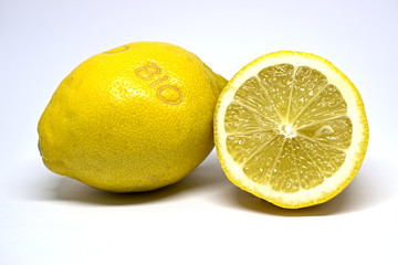 One whole and one halved yellow lemon, laser marked with the German term 'BIO', which means 'organic'