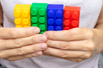 Hands of a woman holding colorful toy plastic bricks, blocks for building, playing games and entertainment concept