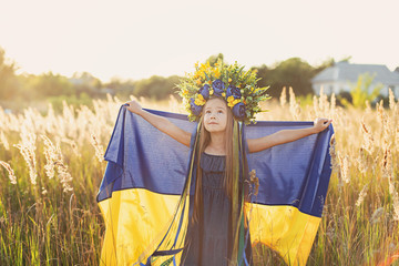 Girl carries fluttering blue and yellow flag of Ukraine in field.