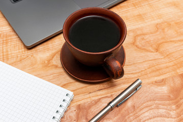 Work wooden office table with laptop, coffee cup, notepad and pen
