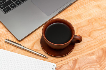 Work wooden office table with laptop, coffee cup, notepad and pen