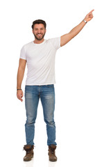 Fototapeta premium Młody Człowiek W Dżinsy I Biały T-shirt Stoi I Kieruje. Przedni widok