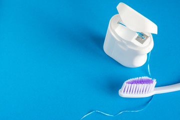 dental floss and toothbrush on a blue background, the concept of care for the oral cavity, preventing tooth decay