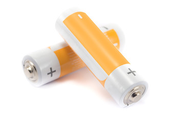 alkaline batteries and orange metal AA-size batteries isolated on white background closeup, carbon...