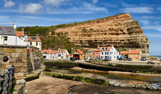 Red cliff of Jurassic strata at the mouth of Staithes Beck emptying into the North Sea at Staithes harbour North York Moors National Park England