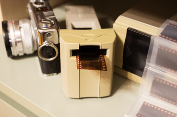 professional film scanner, vintage camera and film segments in the background, film photography, film digitization