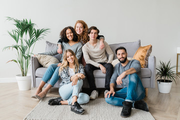 Happy young casual couple and their friends sitting in front of camera