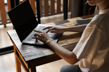 Woman's hands typing on laptop keyboard. Study and work online, freelance. Self employed or freelance woman, girl working with her laptop sitting at wooden table with a phone, smartphone and ereader.