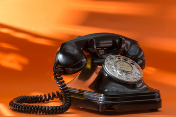 old black telephone, on orange background