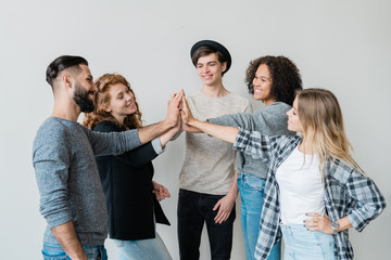 Group of young intercultural friends in casualwear making high-five