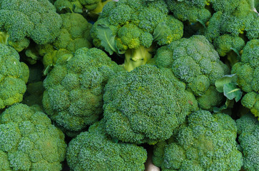 A box of green broccoli heads in a market. - obrazy, fototapety, plakaty