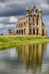 Fototapeta premium Gothic ruin of 13th Century Whitby Abbey on the North Sea with reflection in the water of the Abbey Pond Whitby North York Moors National Park England