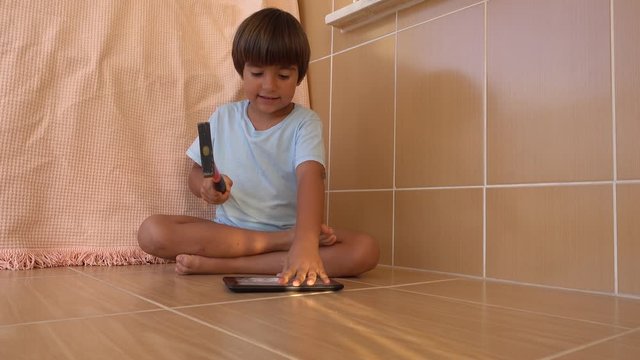 4K Boy tries very hard to open a tablet PC crushing it with a hammer, crystal child