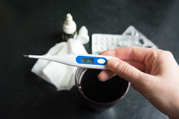 electronic thermometer in hand shows high temperature, fever, disease