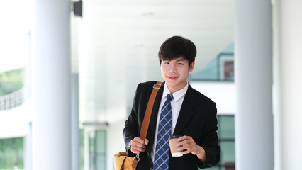 Smiling young businessman holding coffee cup while coffee break.
