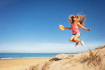 Cute beautiful girl with straw hat jump over beach