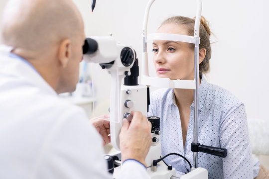 Young female looking at ophthalmologist while having her eyesight examined