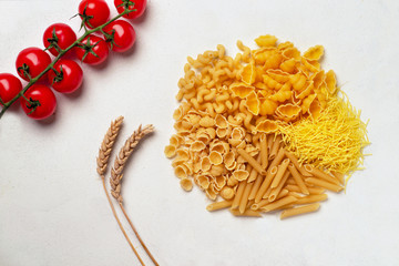 Raw pasta of different types; durum wheat varieties slightly different with cherry tomatoes top view