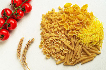 Raw pasta of different types; durum wheat varieties slightly different with cherry tomatoes top view